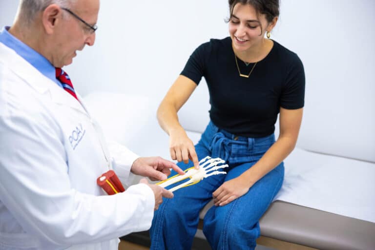 Dr. Grenis showing a patient a model of a hand.