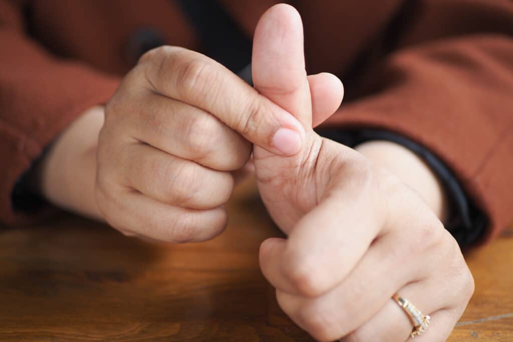 young women hands suffering pain on thumb finger from ganglion cyst