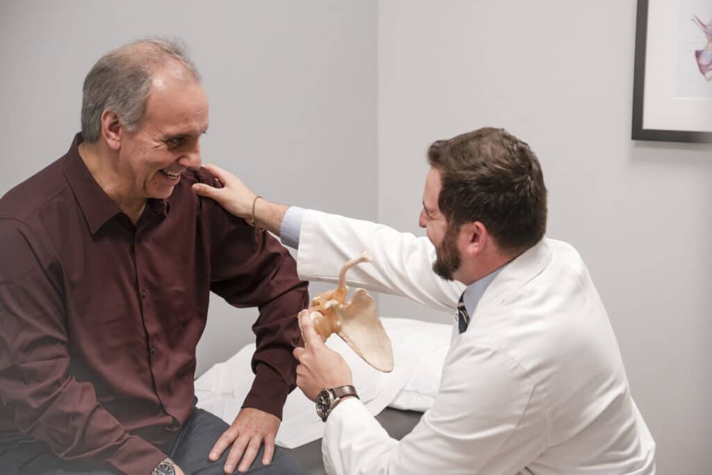 Therapist assisting a patient with gentle shoulder rotation during a frozen shoulder assessment