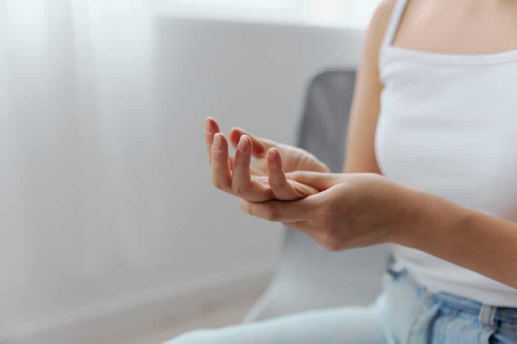 woman grasps right hand with left as she suffers from a hand cramp.