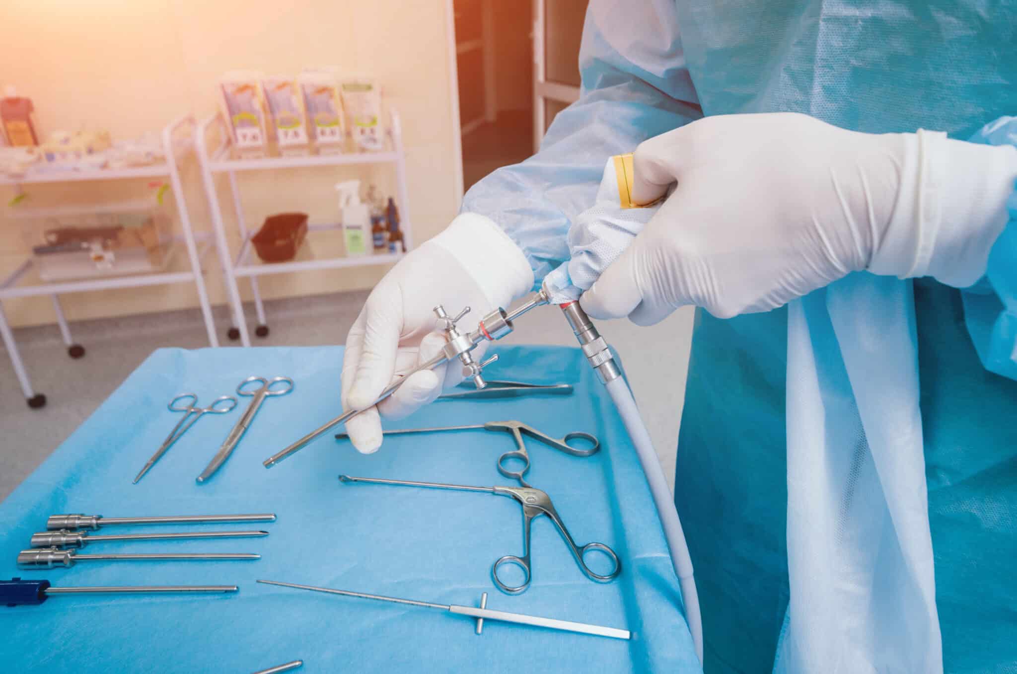 ArthroscopeSurgeryOrthopedicSurgeonsInTeamworkInTheOperatingRoom - Princeton Orthopaedic Associates Gloved and gowned surgeon preparing arthroscopic tools for arthroscopic knee surgery.